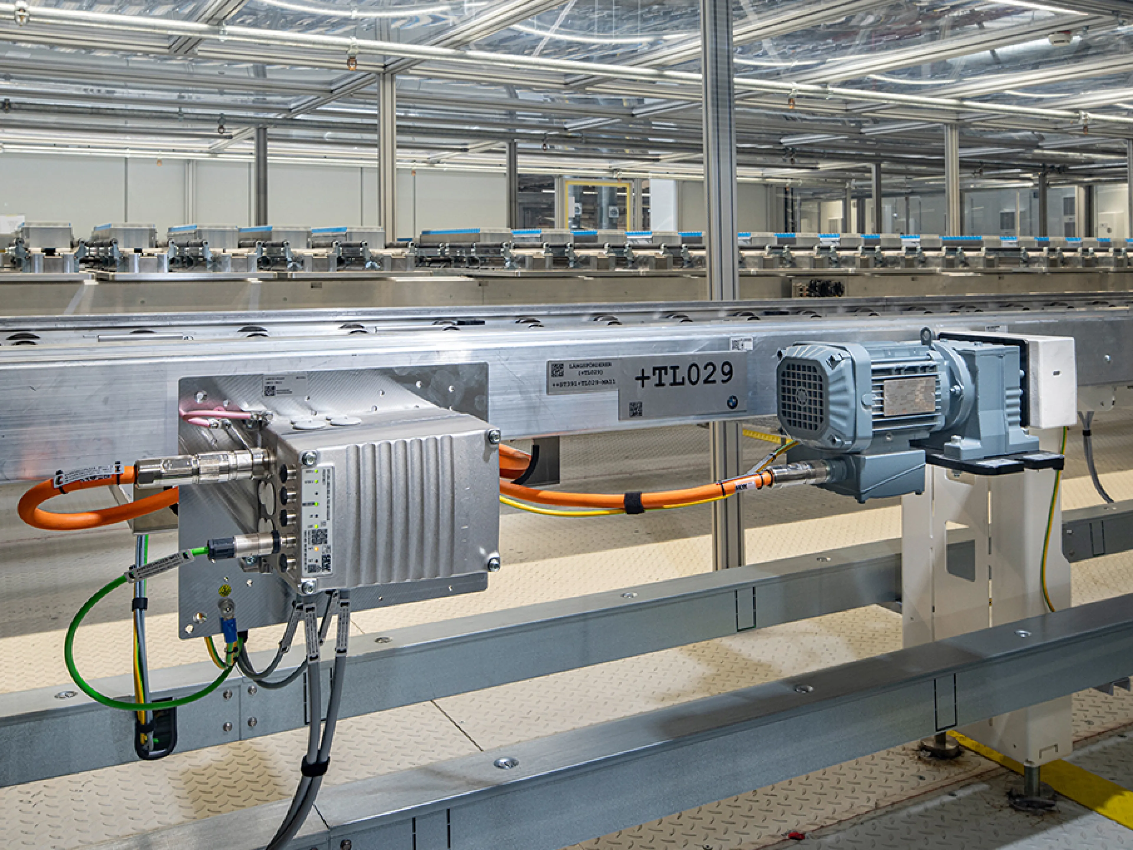 Die Batteriemodulproduktion ist mit Antriebstechnik von SEW-Eurodrive ausgestattet. Der dezentrale Umrichter Movimot flexible (li.) ist für die motornahe Installation vorgesehen. Er speist einen Stirnradgetriebemotor der Baureihe „R..DR..“ mittels Einkabeltechnik (orange). Über die digitale Motorschnittstelle „Movilink DDI“ werden Leistungs-, Bremsen- und Diagnosedaten übertragen. Ein Stirnradgetriebemotor „R..DR..“ treibt die horizontale Fördertechnik in der Pufferzone an, in der die Klebstoffe der Module aushärten, Bild: SEW-Eurodrive Die Batteriemodulproduktion ist mit Antriebstechnik von SEW-Eurodrive ausgestattet. Der dezentrale Umrichter Movimot flexible (li.) ist für die motornahe Installation vorgesehen. Er speist einen Stirnradgetriebemotor der Baureihe „R..DR..“ mittels Einkabeltechnik (orange). Über die digitale Motorschnittstelle „Movilink DDI“ werden Leistungs-, Bremsen- und Diagnosedaten übertragen.